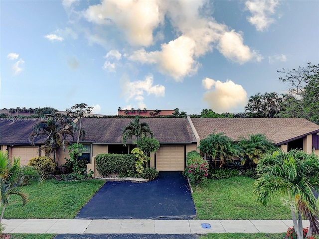 9530 W Daffodil Ln, Miramar, FL 33025 - view of front of house with asphalt driveway, an attached garage, a front yard, stucco siding, and a shingled roof