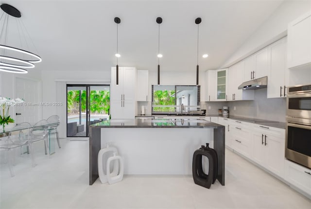 13526 Jonquil Pl, Wellington, FL 33414 - kitchen featuring dark countertops, a kitchen island, glass insert cabinets, white cabinetry, and recessed lighting
