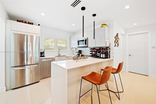 2511 Tequesta Ln, Coconut Grove, FL 33133 - kitchen with appliances with stainless steel finishes, a kitchen bar, light countertops, a peninsula, and recessed lighting