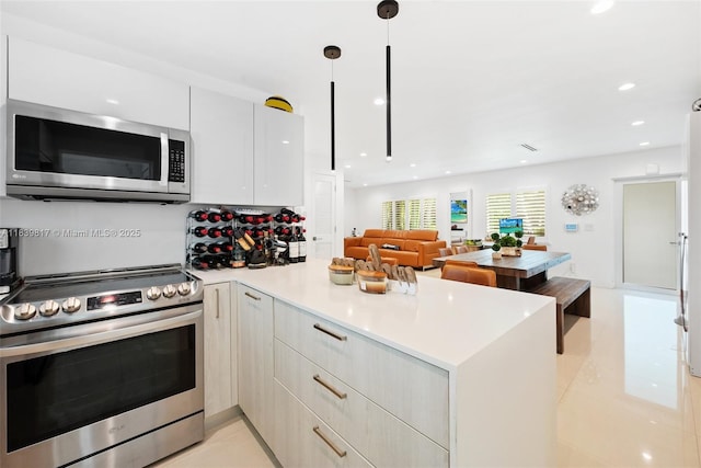2511 Tequesta Ln, Coconut Grove, FL 33133 - kitchen featuring stainless steel appliances, a peninsula, modern cabinets, light countertops, and white cabinetry