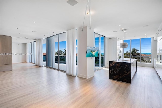 5959 Collins Ave Unit 705, Miami Beach, FL 33140 - unfurnished living room featuring a wall of windows, light wood-style flooring, and healthy amount of natural light