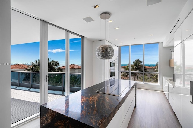 5959 Collins Ave Unit 705, Miami Beach, FL 33140 - kitchen with modern cabinets, floor to ceiling windows, light wood-type flooring, white cabinets, and plenty of natural light
