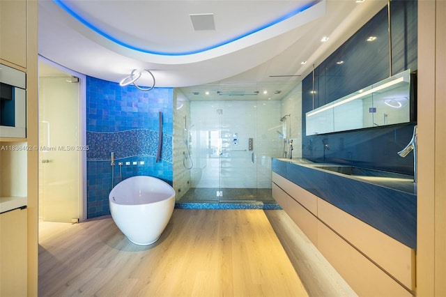 5959 Collins Ave Unit 705, Miami Beach, FL 33140 - bathroom with vanity, a stall shower, wood finished floors, a soaking tub, and tile walls