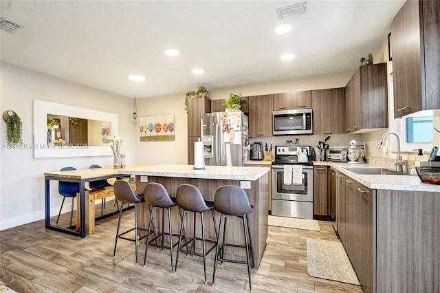 8657 SW 22nd Ct, Miramar, FL 33025 - kitchen with a kitchen bar, stainless steel appliances, light wood-type flooring, light countertops, and a center island