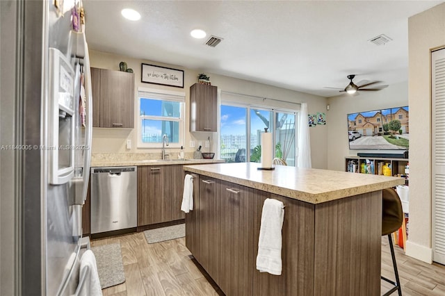 8657 SW 22nd Ct, Miramar, FL 33025 - kitchen featuring appliances with stainless steel finishes, a breakfast bar area, light countertops, a kitchen island, and light wood-type flooring