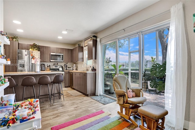 8657 SW 22nd Ct, Miramar, FL 33025 - kitchen featuring a kitchen bar, light countertops, appliances with stainless steel finishes, a peninsula, and light wood-type flooring