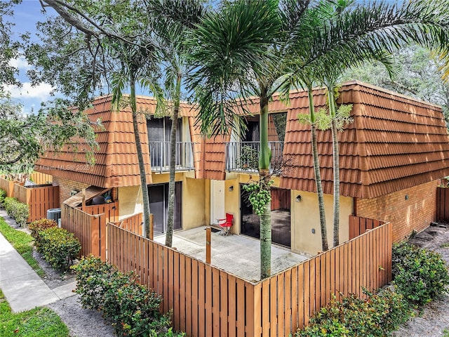 135 Heritage Way, West Palm Beach, FL 33407 - back of house featuring a balcony, brick siding, a tile roof, and mansard roof