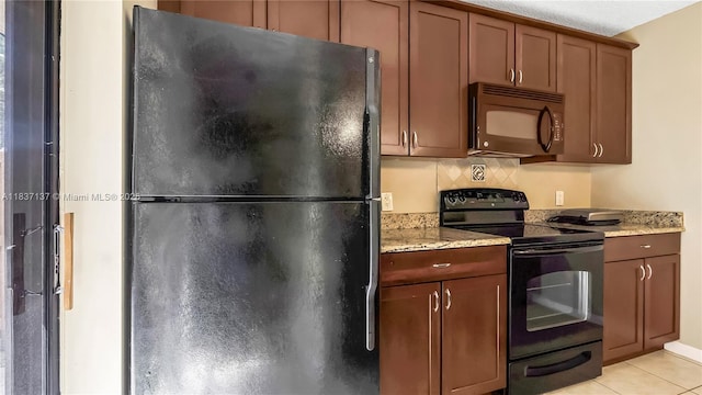 135 Heritage Way, West Palm Beach, FL 33407 - kitchen with black appliances, light tile patterned floors, light stone countertops, and brown cabinets