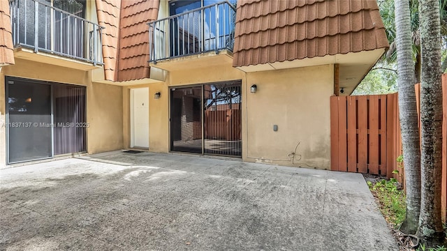 135 Heritage Way, West Palm Beach, FL 33407 - property entrance with a tiled roof, stucco siding, a patio, mansard roof, and a balcony