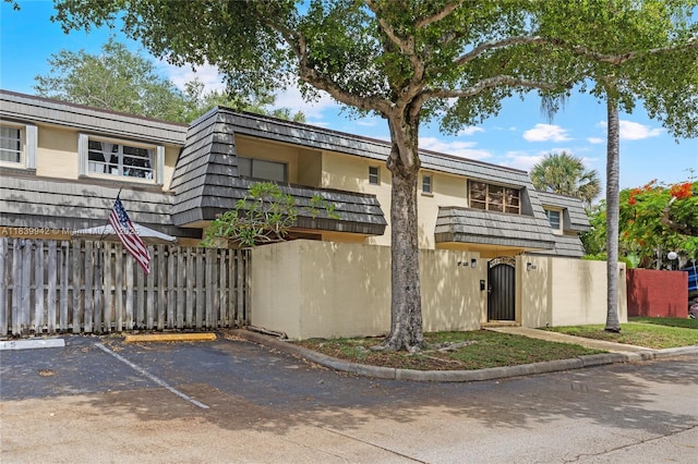 8713 SW 137th Ave Unit 8713, Miami, FL 33183 - view of front of house featuring a balcony, uncovered parking, a fenced front yard, and mansard roof