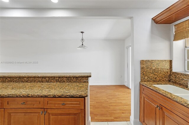 8713 SW 137th Ave Unit 8713, Miami, FL 33183 - kitchen featuring dark stone countertops, brown cabinetry, recessed lighting, decorative light fixtures, and light wood-type flooring