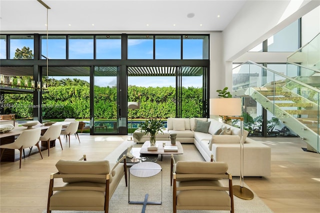 967 NE 117th St, Biscayne Park, FL 33161 - living area with stairway, wood finished floors, a towering ceiling, and a wall of windows