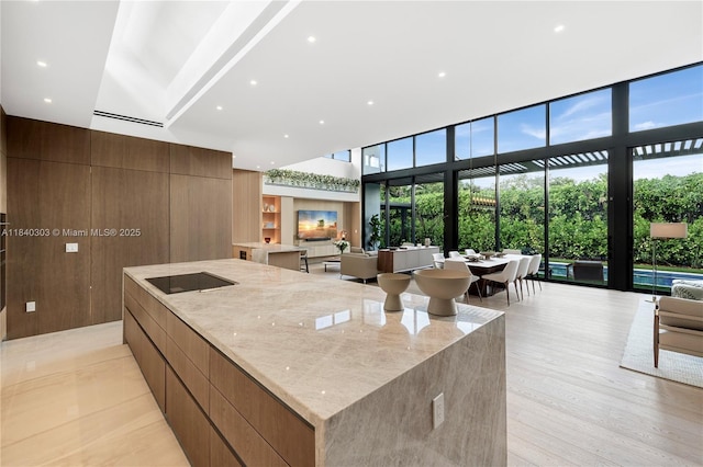 967 NE 117th St, Biscayne Park, FL 33161 - kitchen featuring modern cabinets, a large island, a high ceiling, light stone countertops, and black electric stovetop