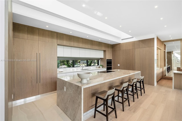 967 NE 117th St, Biscayne Park, FL 33161 - kitchen featuring a large island, modern cabinets, a kitchen breakfast bar, light stone countertops, and recessed lighting