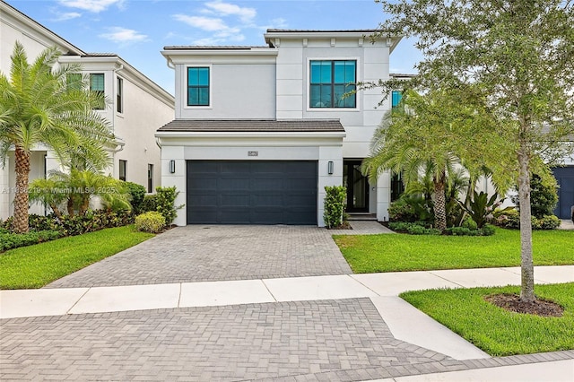 13467 Artisan Cir, Palm Beach Gardens, FL 33418 - view of front of property featuring decorative driveway, an attached garage, a front yard, a tiled roof, and stucco siding