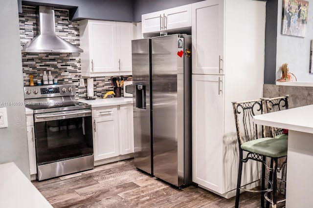 1004 NE 151st Ter, North Miami Beach, FL 33162 - kitchen featuring stainless steel appliances, wall chimney exhaust hood, light countertops, white cabinets, and light wood finished floors