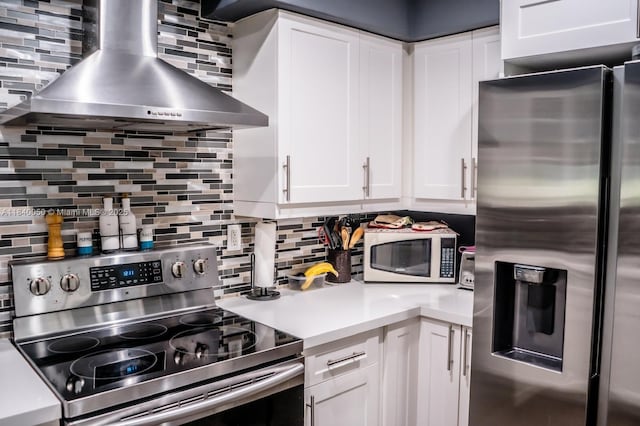 1004 NE 151st Ter, North Miami Beach, FL 33162 - kitchen with appliances with stainless steel finishes, wall chimney exhaust hood, decorative backsplash, white cabinetry, and light countertops