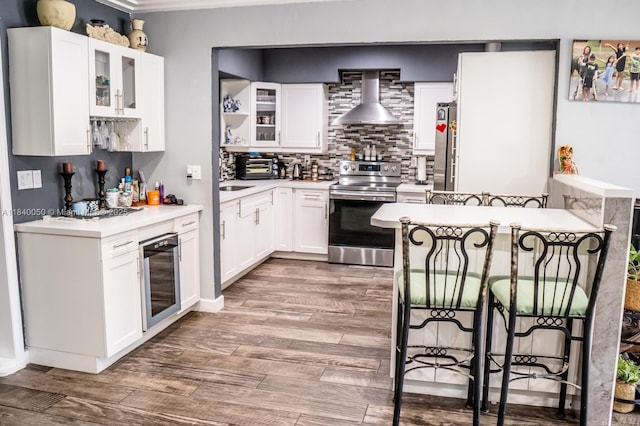 1004 NE 151st Ter, North Miami Beach, FL 33162 - kitchen featuring stainless steel appliances, a breakfast bar area, wall chimney exhaust hood, backsplash, and light wood-style flooring