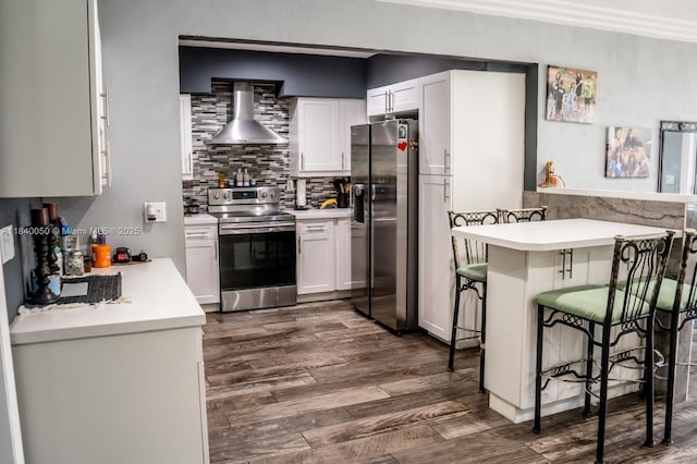 1004 NE 151st Ter, North Miami Beach, FL 33162 - kitchen with stainless steel appliances, wall chimney exhaust hood, a breakfast bar, light countertops, and dark wood-style flooring