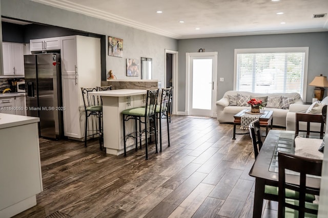 1004 NE 151st Ter, North Miami Beach, FL 33162 - kitchen featuring ornamental molding, stainless steel fridge, light countertops, a kitchen bar, and dark wood-style floors