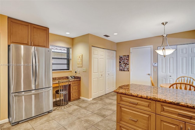 53 Northwoods Ln, Boynton Beach, FL 33436 - kitchen featuring freestanding refrigerator, light stone counters, light tile patterned floors, hanging light fixtures, and brown cabinets