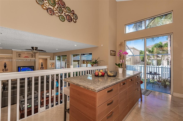 2188 NW 158th Ave, Pembroke Pines, FL 33028 - kitchen featuring a kitchen island, ceiling fan, light stone counters, a towering ceiling, and a breakfast bar