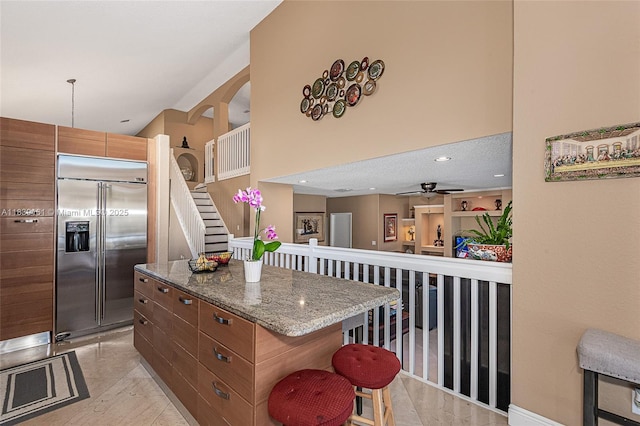 2188 NW 158th Ave, Pembroke Pines, FL 33028 - kitchen with built in fridge, a breakfast bar, ceiling fan, light stone counters, and a center island