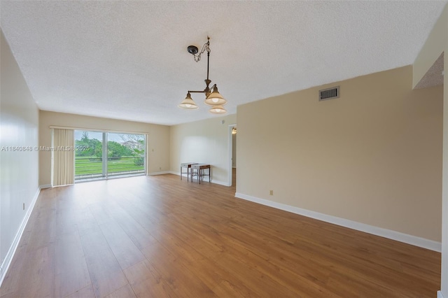 3581 Inverrary Dr Unit 308, Lauderhill, FL 33319 - unfurnished living room with a chandelier, light wood finished floors, and a textured ceiling