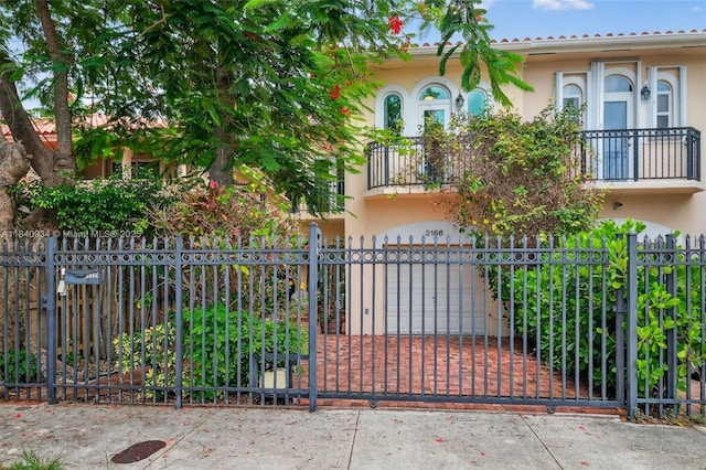 3166 Indiana St Unit I, Miami, FL 33133 - view of front of home featuring stucco siding, a balcony, a fenced front yard, driveway, and a gate