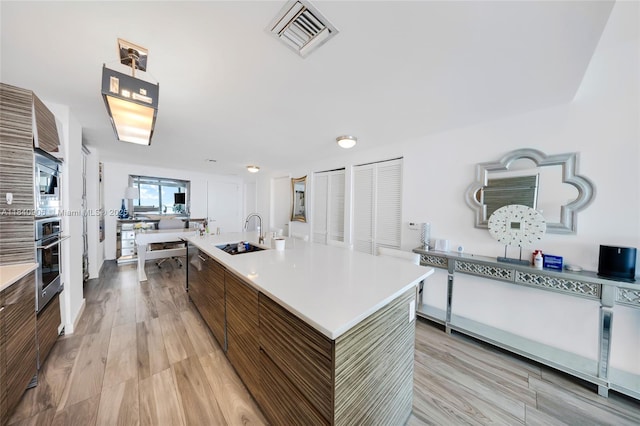 460 NE 28th St Unit 3905, Miami, FL 33137 - kitchen featuring light countertops, light wood-type flooring, modern cabinets, and a kitchen island with sink