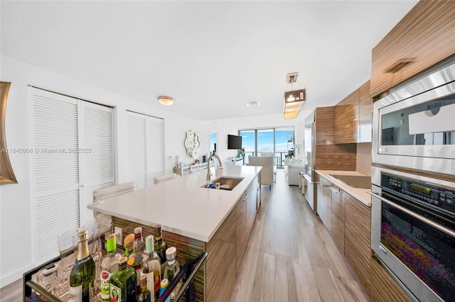 460 NE 28th St Unit 3905, Miami, FL 33137 - kitchen with modern cabinets, stainless steel appliances, light countertops, a center island with sink, and brown cabinets