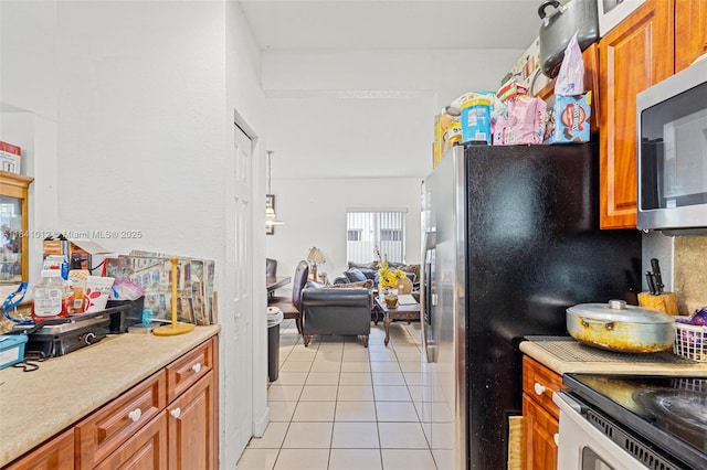 3135 NE 4th St, Homestead, FL 33033 - kitchen featuring light tile patterned floors, light countertops, stainless steel microwave, and brown cabinetry