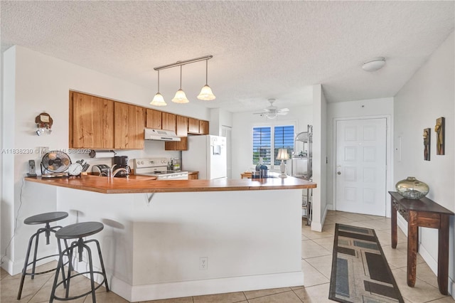 2215 Cypress Island Dr Unit 707, Pompano Beach, FL 33069 - kitchen featuring a peninsula, white appliances, brown cabinets, decorative light fixtures, and light tile patterned floors