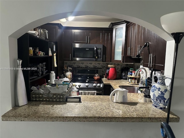 13810 SW 112th St Unit 106, Miami, FL 33186 - kitchen featuring arched walkways, appliances with stainless steel finishes, dark brown cabinetry, and light stone countertops