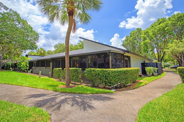 16041 Fairway Ter Unit 121, Weston, FL 33326 - view of side of home featuring a sunroom, a lawn, and stucco siding