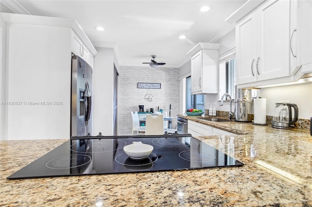 16041 Fairway Ter Unit 121, Weston, FL 33326 - kitchen with ornamental molding, black electric stovetop, white cabinets, light stone countertops, and ceiling fan