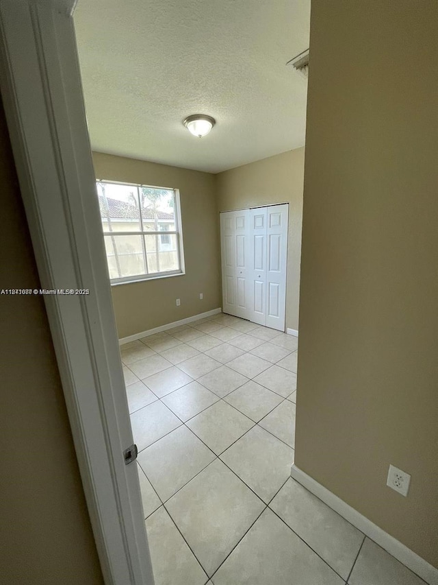 1666 SE 27th Ct Unit 208, Homestead, FL 33035 - unfurnished bedroom with a textured ceiling, light tile patterned floors, and a closet