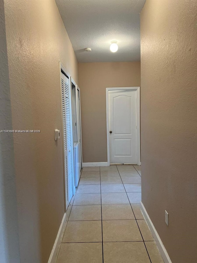 1666 SE 27th Ct Unit 208, Homestead, FL 33035 - hall featuring light tile patterned floors, a textured wall, and a textured ceiling