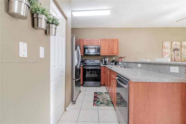 14053 SW 49th St Unit 7, Miramar, FL 33027 - kitchen with stainless steel appliances, light tile patterned flooring, light countertops, brown cabinetry, and a peninsula