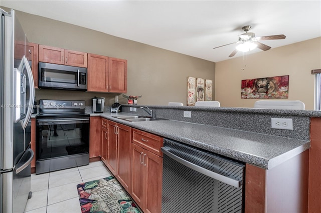 14053 SW 49th St Unit 7, Miramar, FL 33027 - kitchen featuring stainless steel appliances, a peninsula, a ceiling fan, dark countertops, and brown cabinets