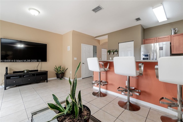 14053 SW 49th St Unit 7, Miramar, FL 33027 - kitchen featuring stainless steel fridge with ice dispenser, a kitchen bar, light tile patterned floors, and brown cabinetry