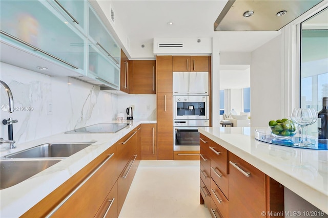 kitchen featuring black electric stovetop, sink, and tasteful backsplash