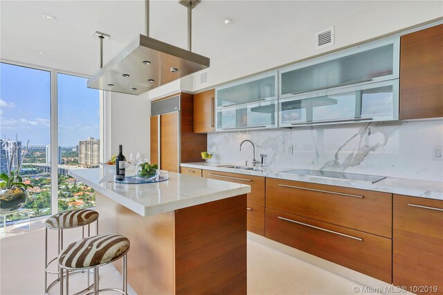 kitchen featuring a center island, black electric stovetop, backsplash, and plenty of natural light