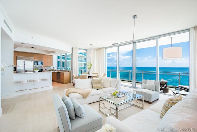 living room featuring crown molding, a water view, and a wall of windows