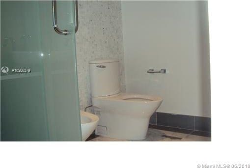 bathroom featuring toilet and a shower with shower door