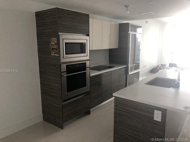 kitchen featuring stainless steel appliances, white cabinetry, sink, and light tile patterned floors