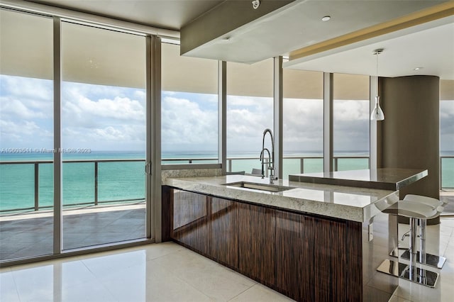 kitchen with stone counters, a water view, pendant lighting, sink, and light tile patterned floors