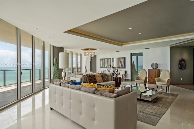 living room with a water view, a wealth of natural light, light tile patterned floors, and a tray ceiling