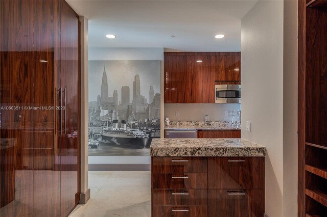 kitchen with light stone counters, stainless steel microwave, and light tile patterned floors