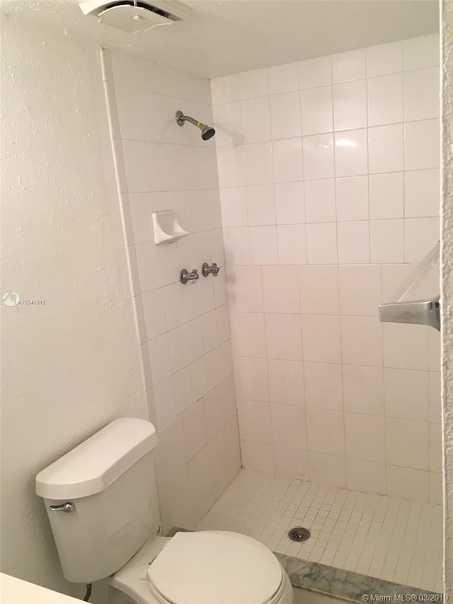 bathroom with toilet and a tile shower